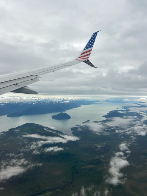Airplane wing above islands and clouds in Alaska