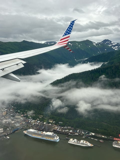 Airplane wing over a cloudy Alaska coastline