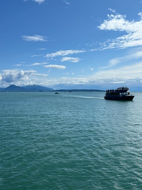 Boat on blue Alaska bay with mountain backdrop