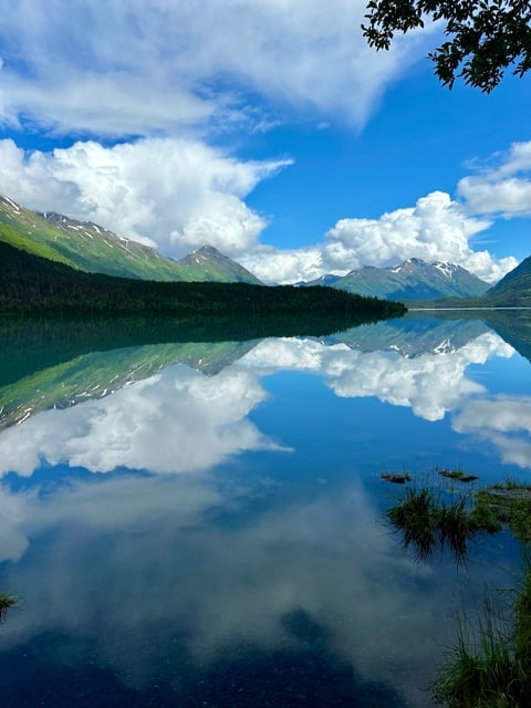 Calm Alaska lake reflecting clouds and mountains