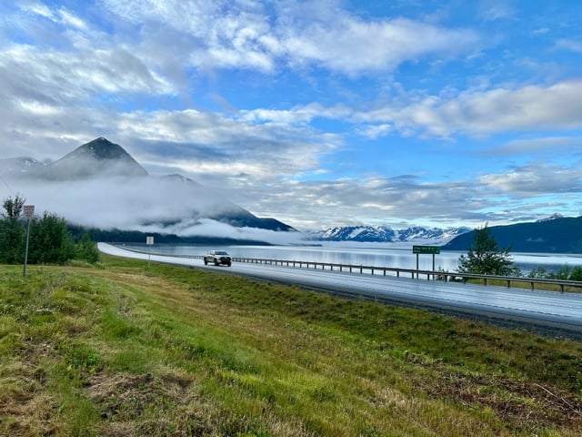 Coastal Alaska road beside mountains and water