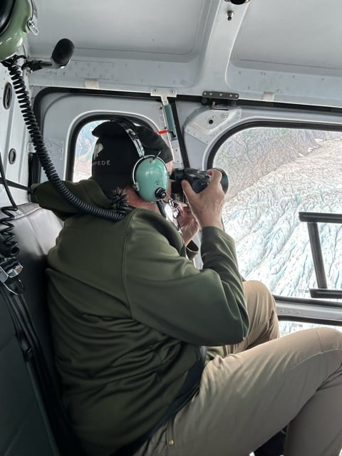 Photographer inside a helicopter over Alaska terrain