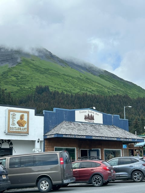 Roadside storefront below green Alaska mountains