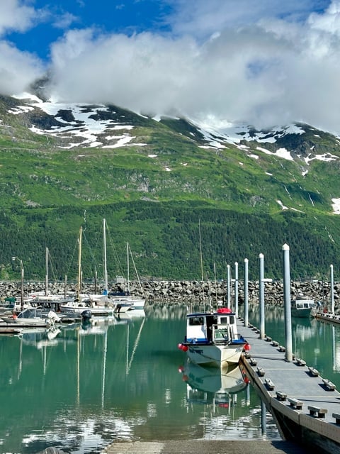 Sailboats in an Alaska harbor below misty mountains