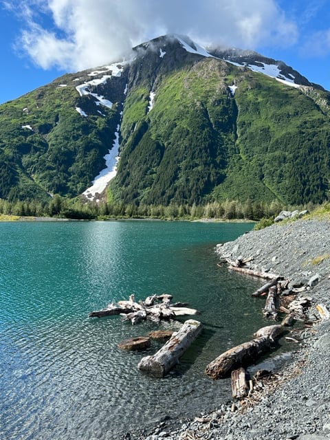 Turquoise Alaska lake with kayaks below snowy mountains