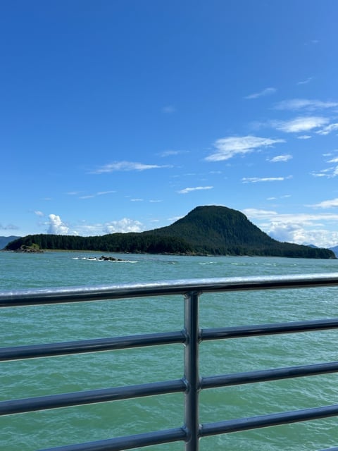 Turquoise Alaska water and island seen from a boat deck
